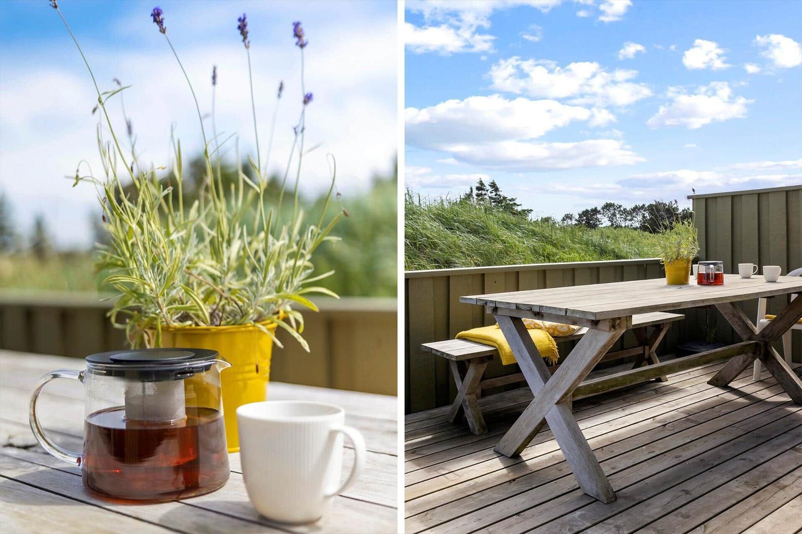 Terrasse mit Tisch, Bänken und Lavendel. Tasse und Teekanne auf Holztisch.
