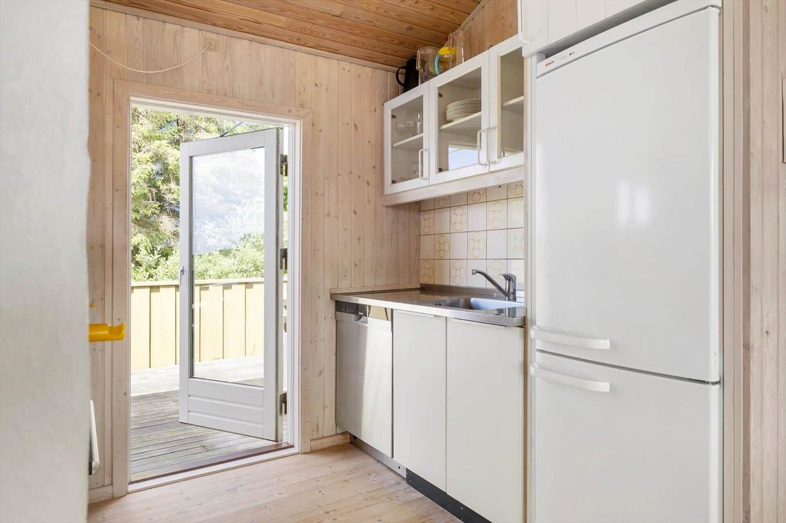 Küche mit Kühlschrank, Spüle und Tür zum Balkon