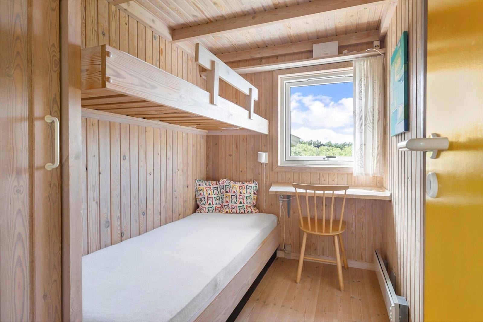 Zimmer mit Schlafcouch, Doppelstockbett und Schreibtisch mit Stuhl.