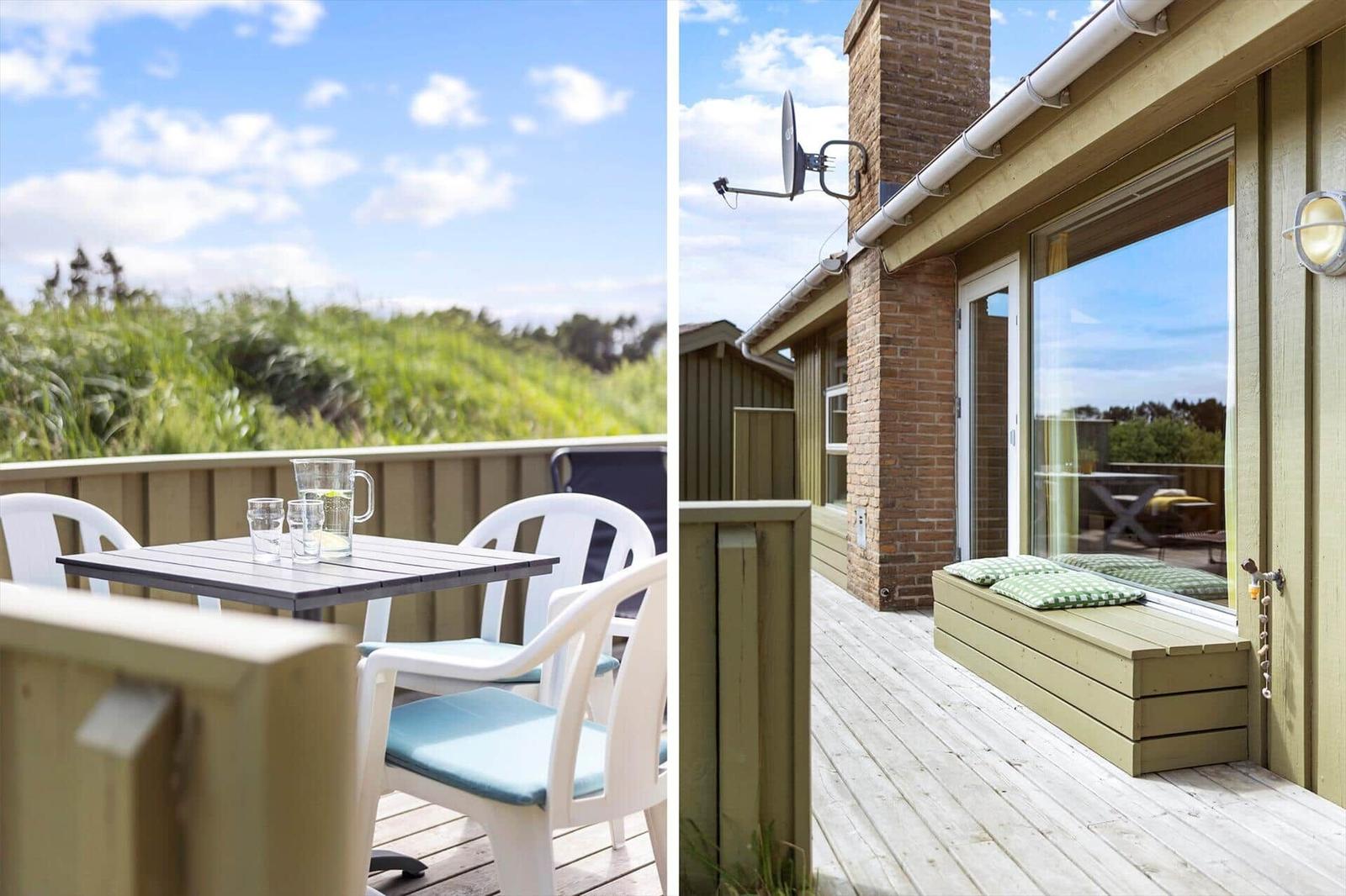 Terrasse mit Tisch und Stühlen, Blick auf Grünland. Holzterrasse mit Sitzbank und Fenster.