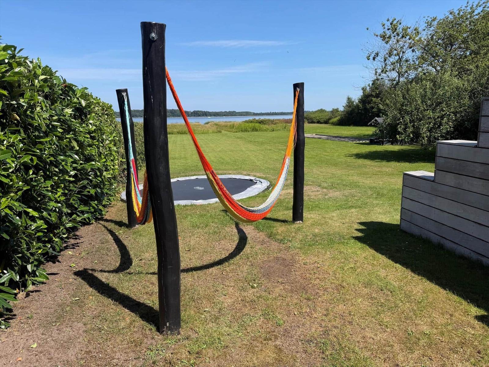Farbiger Hängemattenbereich mit Trampolin und Blick auf den See.