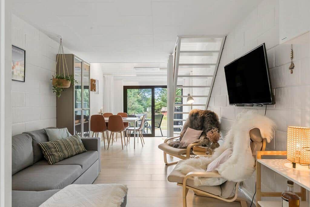 Living area with sofa, dining area, and staircase to upper level.