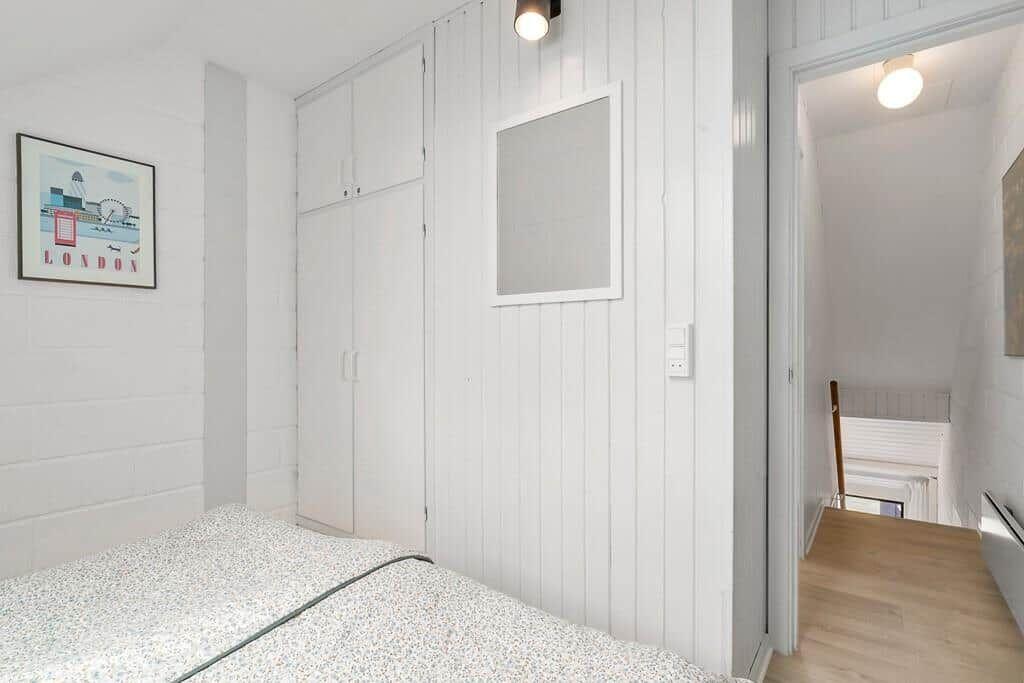Bedroom with bed, closet, and wall art. Door leads to a hallway.