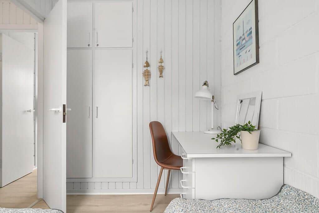 Desk with chair, plant, and lamp next to wardrobe.