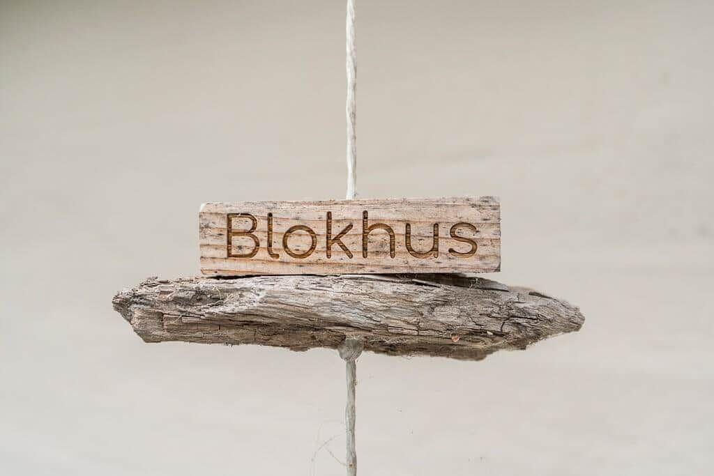 A wooden sign reading Blokhus hangs on a rope.