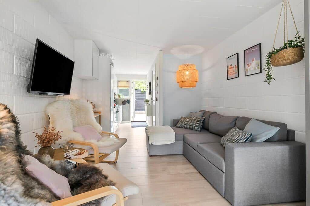 Living area with sofa, TV, and hanging plant on the wall.