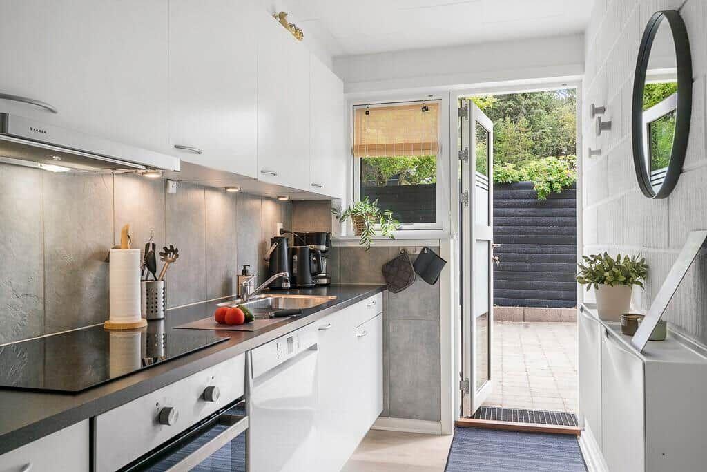 Kitchen with white cabinets, dark countertop, and view to the garden.