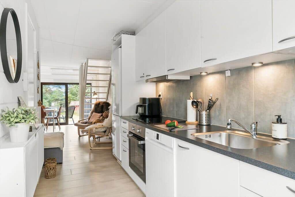 Kitchen with white cabinets, stainless steel sink, and view into living area.