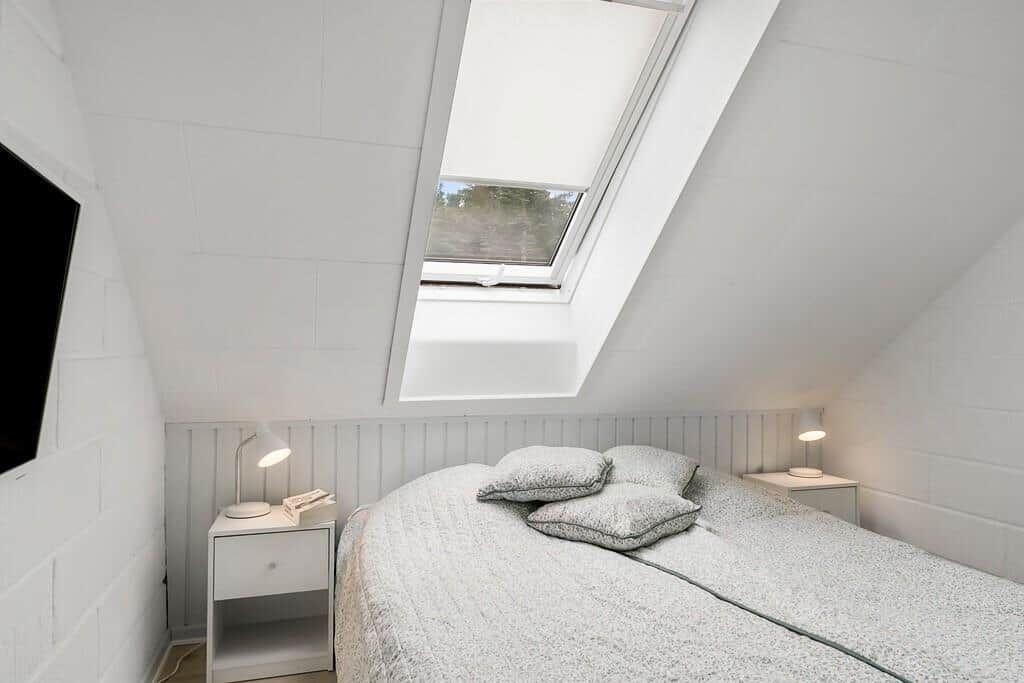 Bedroom with skylight, bed, nightstands, and wall-mounted TV.