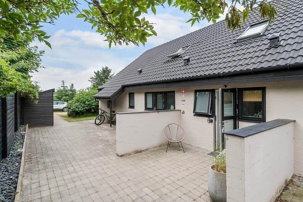 House with terrace, garden, and bicycle. Roof with skylights. Paved path and greenery.