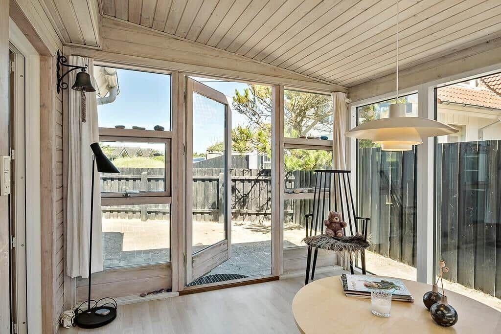 A room with large windows, a door to the outside area, and a round table.