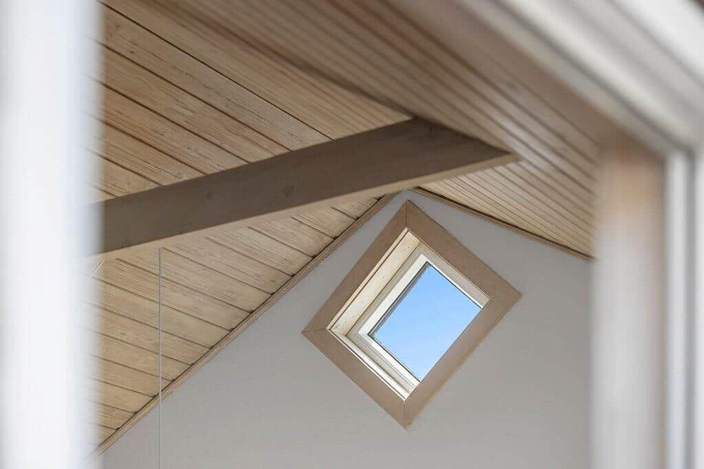 Skylight in a room with wooden ceiling and white walls.