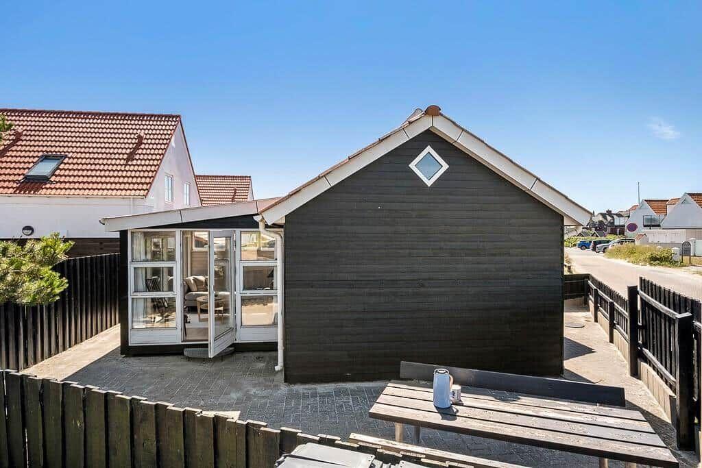 Wooden house with terrace and seating. Glass door leads to interior.