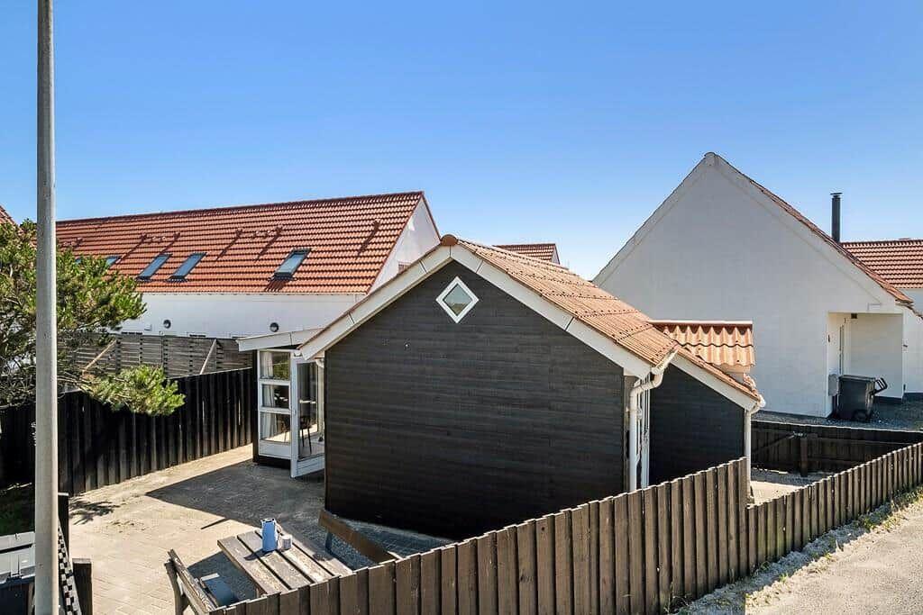 Wooden house with terrace and garden fence. Backyard with table and chairs.