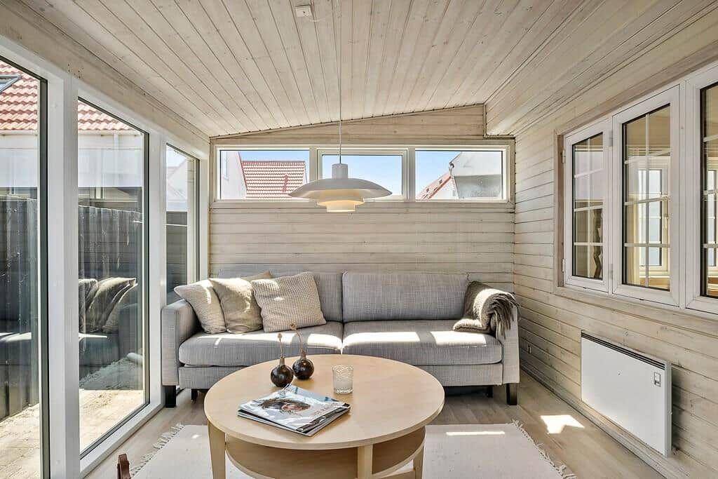 Living area with sofa, round table, and wood walls. Large windows and skylight.