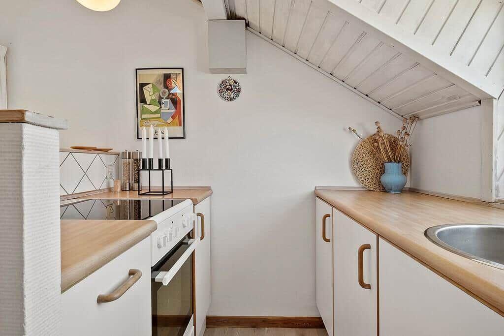 Kitchen with wooden surfaces, white cabinets, and sloped ceiling.