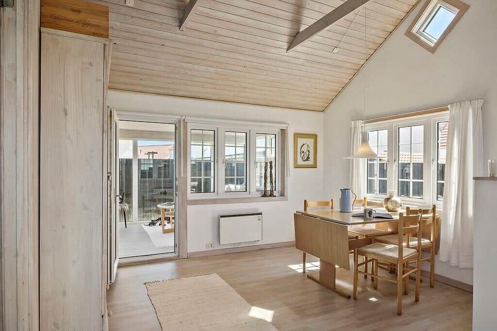 Dining room with wooden table, chairs, and windows. Attic with skylight and wooden ceiling.