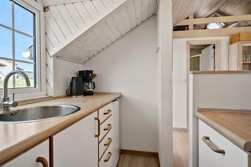 Kitchen with wooden surfaces, stainless steel sink, and window under gable roof.