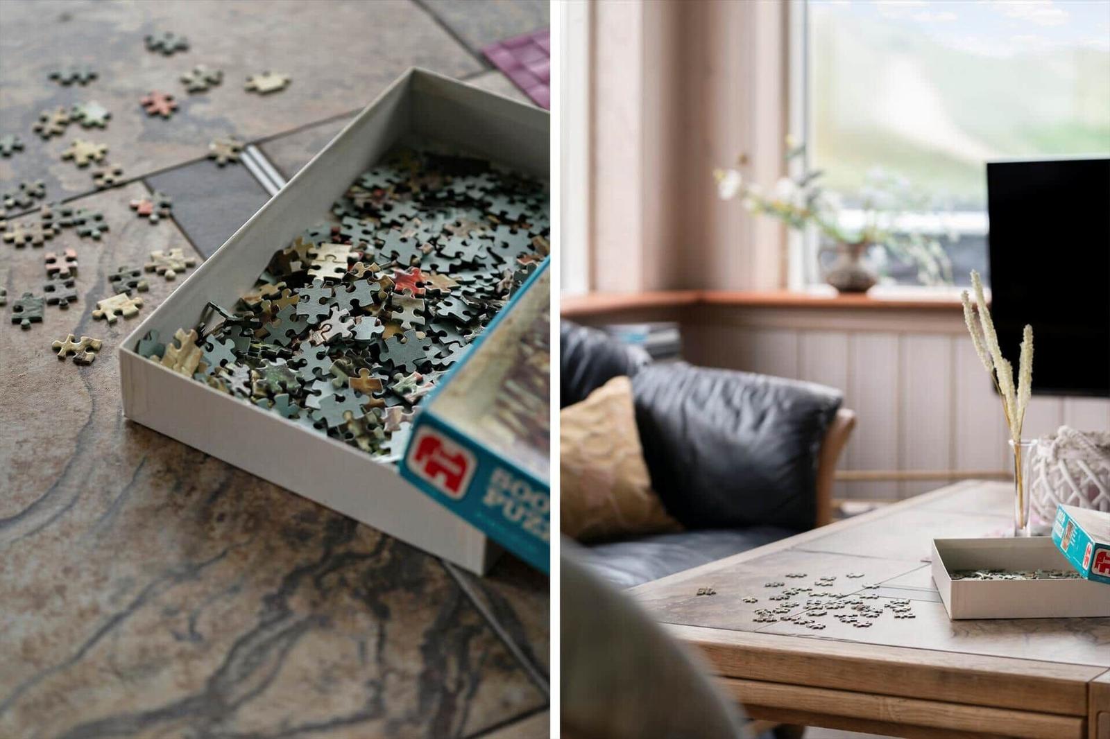 Puzzle-Teile liegen auf dem Boden und Tisch. Ein Sofa und Fenster sind sichtbar.