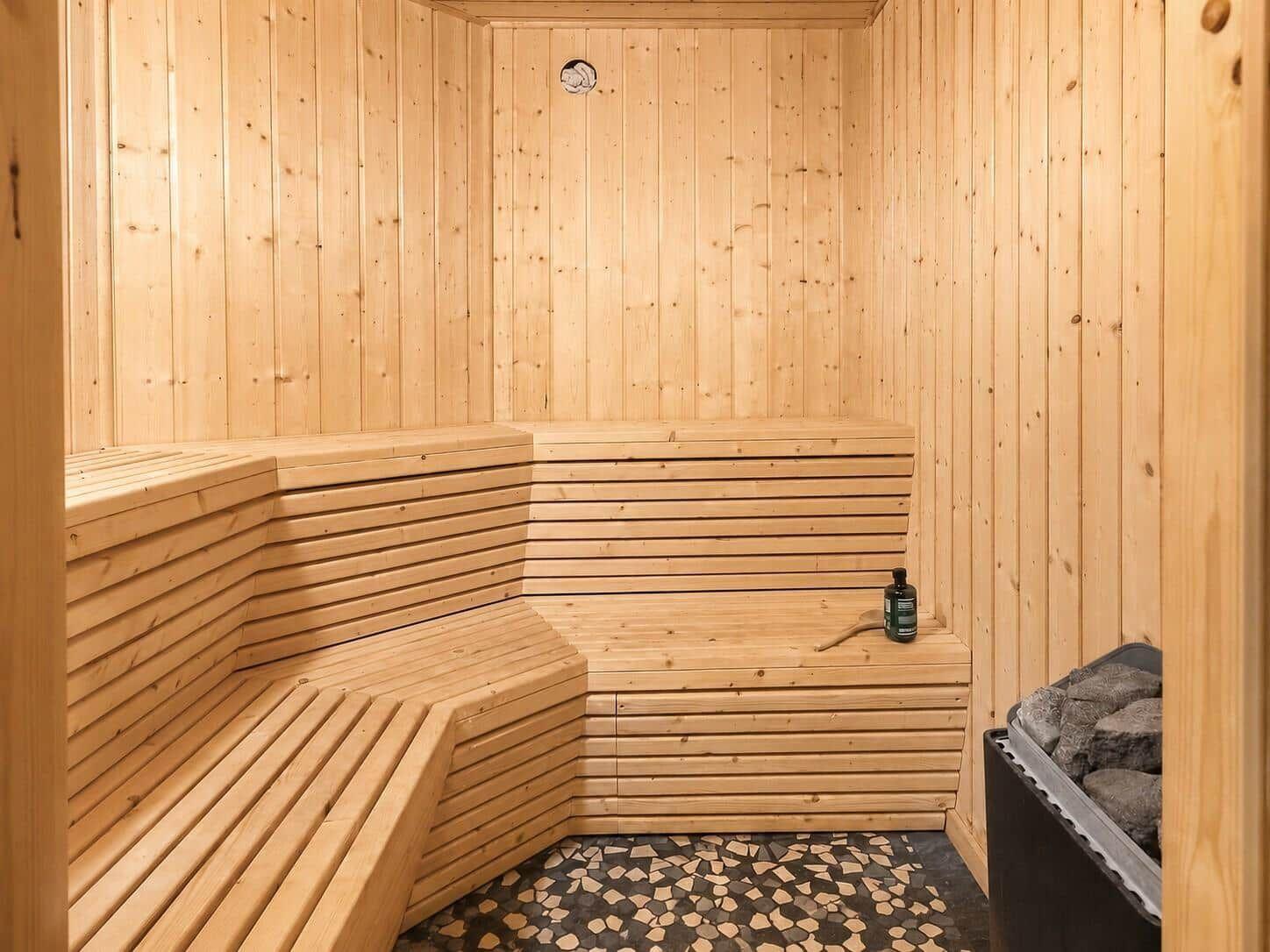Sauna mit Holzbank und Steinmulde. Holzwände und Mosaikboden.