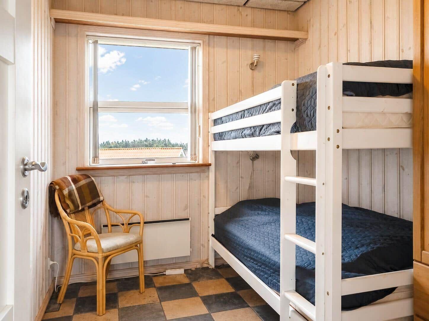 Zimmer mit Doppelstockbett, Stuhl und Fenster mit Blick.