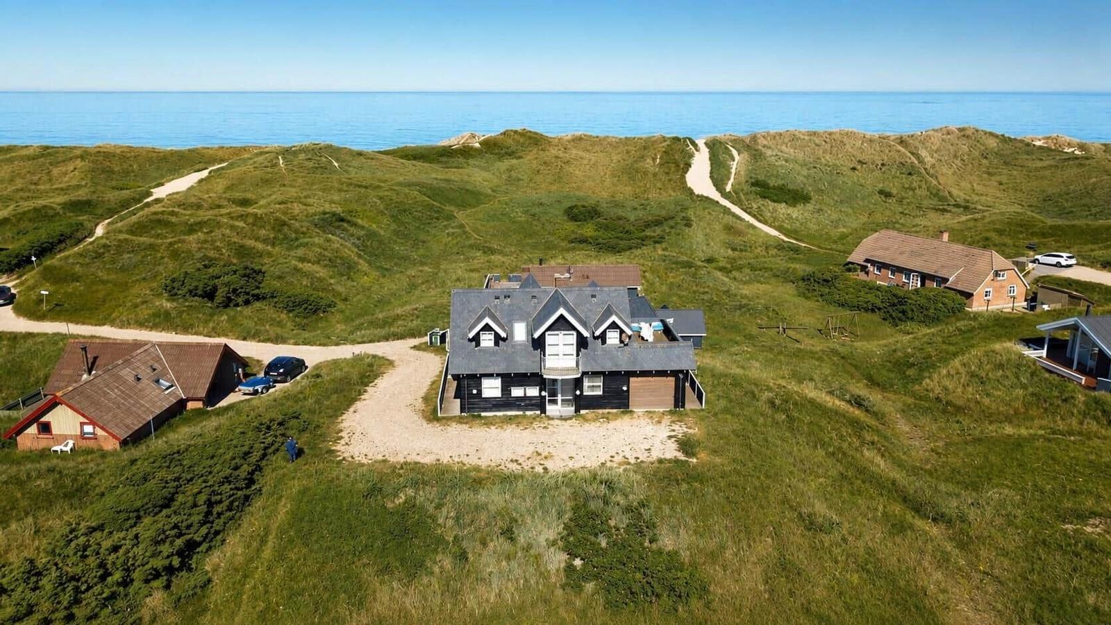 Haus auf Dünen mit Blick auf das Meer und gepflasterten Wegen.