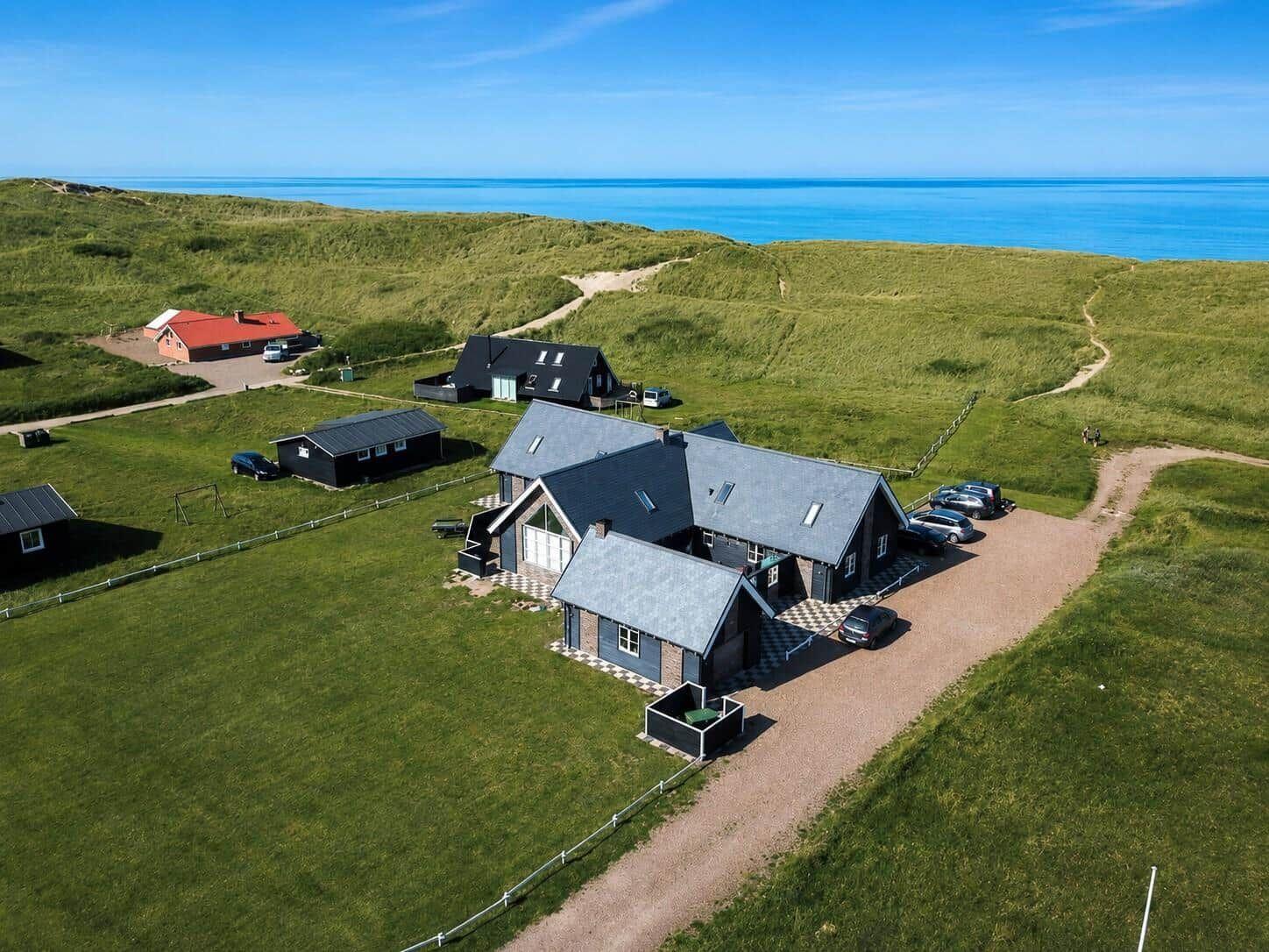 Haus mit Garage und Parkplätzen in grüner Umgebung mit Blick aufs Meer.
