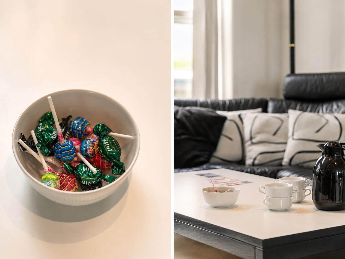 Eine Schale mit Lutschern und eine Couch mit Kissen und Tischset.