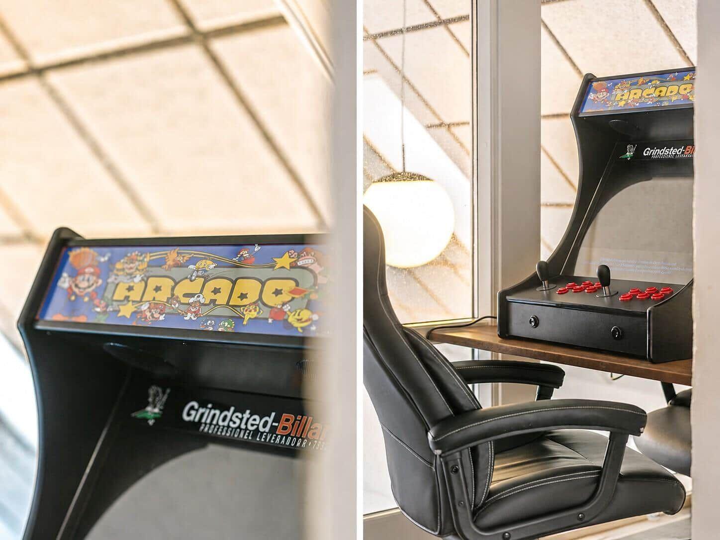 Arcade-Spielautomat mit Stuhl vor Fenster