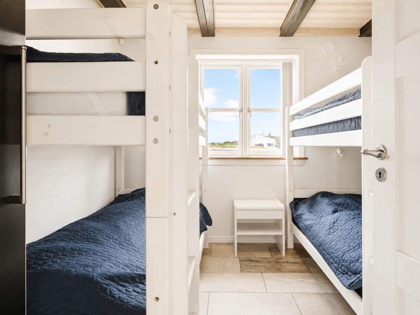 Zimmer mit zwei Etagenbetten, Fenster und kleinem Tisch