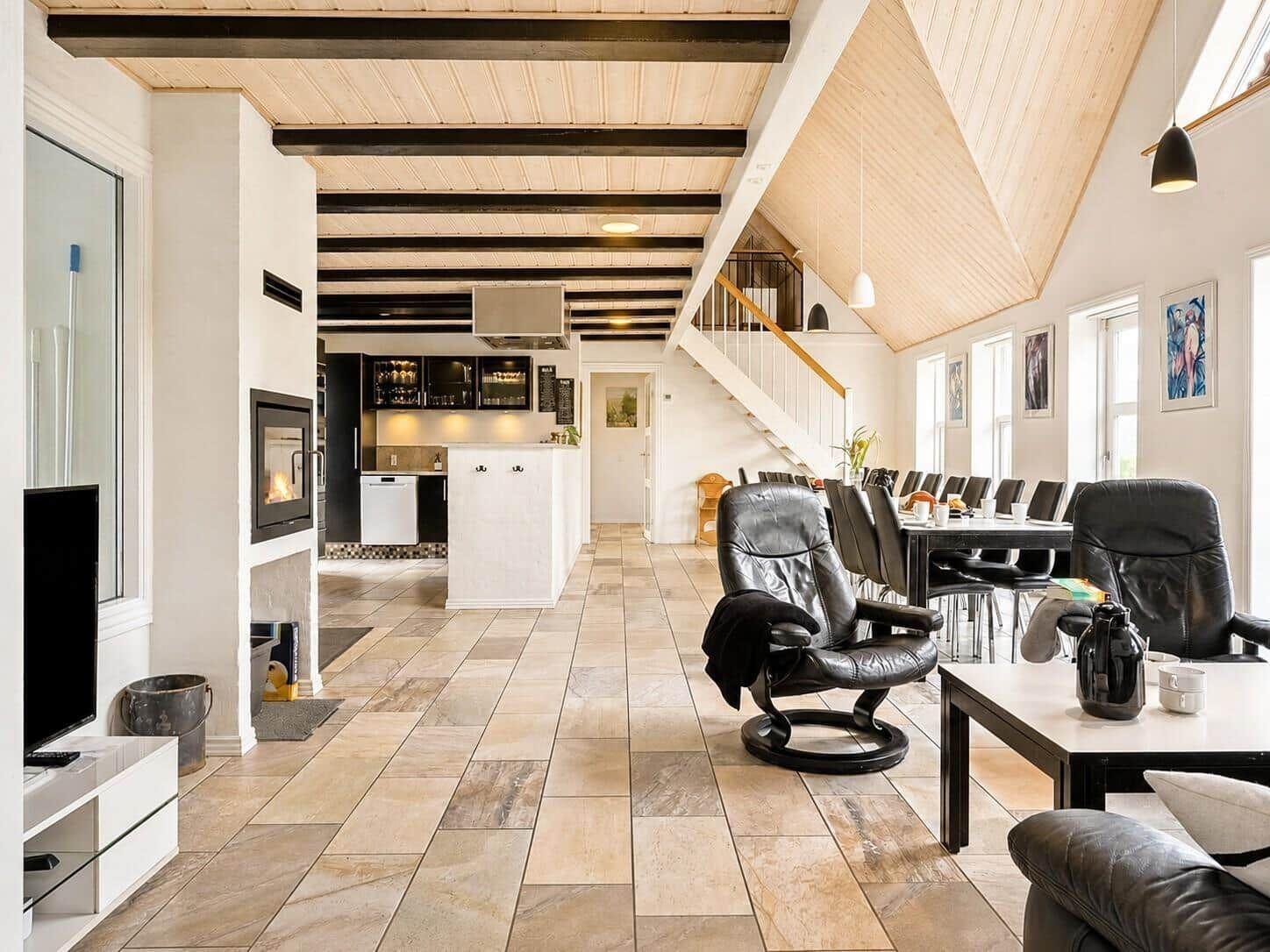 Wohn- und Essbereich mit Kamin, Küche und Treppe zur oberen Etage.