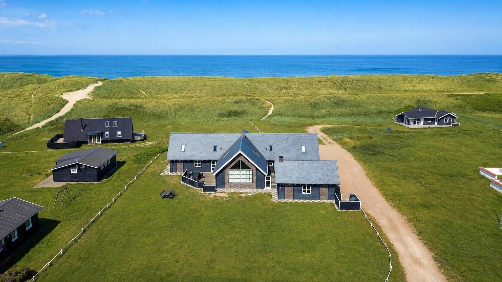 Haus mit Terrasse und Garten, umgeben von Grasland und Meer.