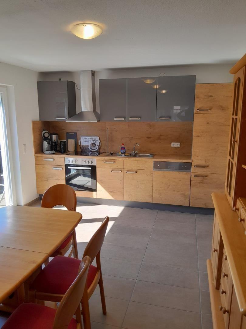 Küche mit Holzschränken, Edelstahlgeräten und Essbereich mit Holztisch.