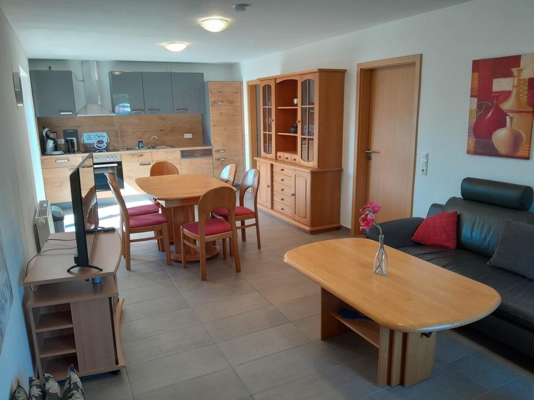 Wohn- und Essbereich mit Küche, Sofa, Esstisch und Holzmöbel.