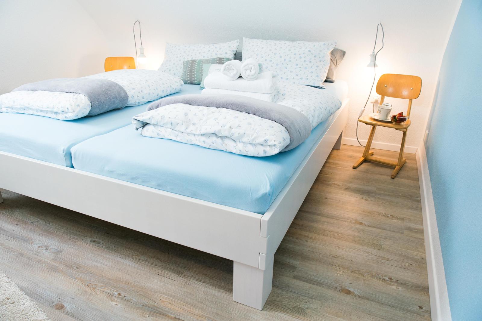 Ein Schlafzimmer mit Doppelbett, hellblauen Bettwäsche und Holzfußboden.