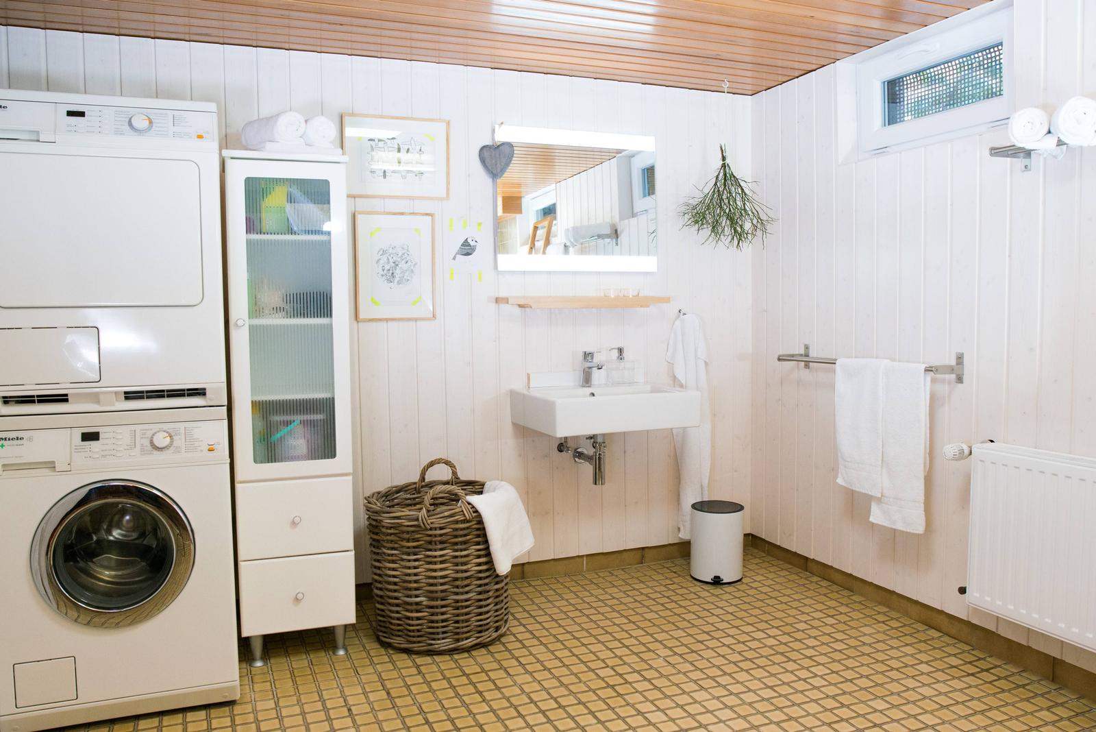 Badezimmer mit Waschmaschine, Spiegelschrank und Badewannenbereich.