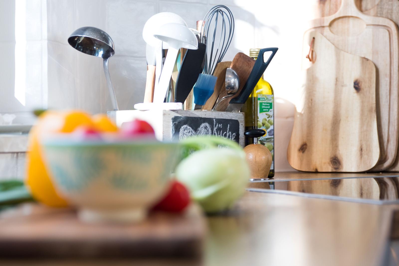Küchenbereich mit Obst, Küchenutensilien und einem Holzbrett.