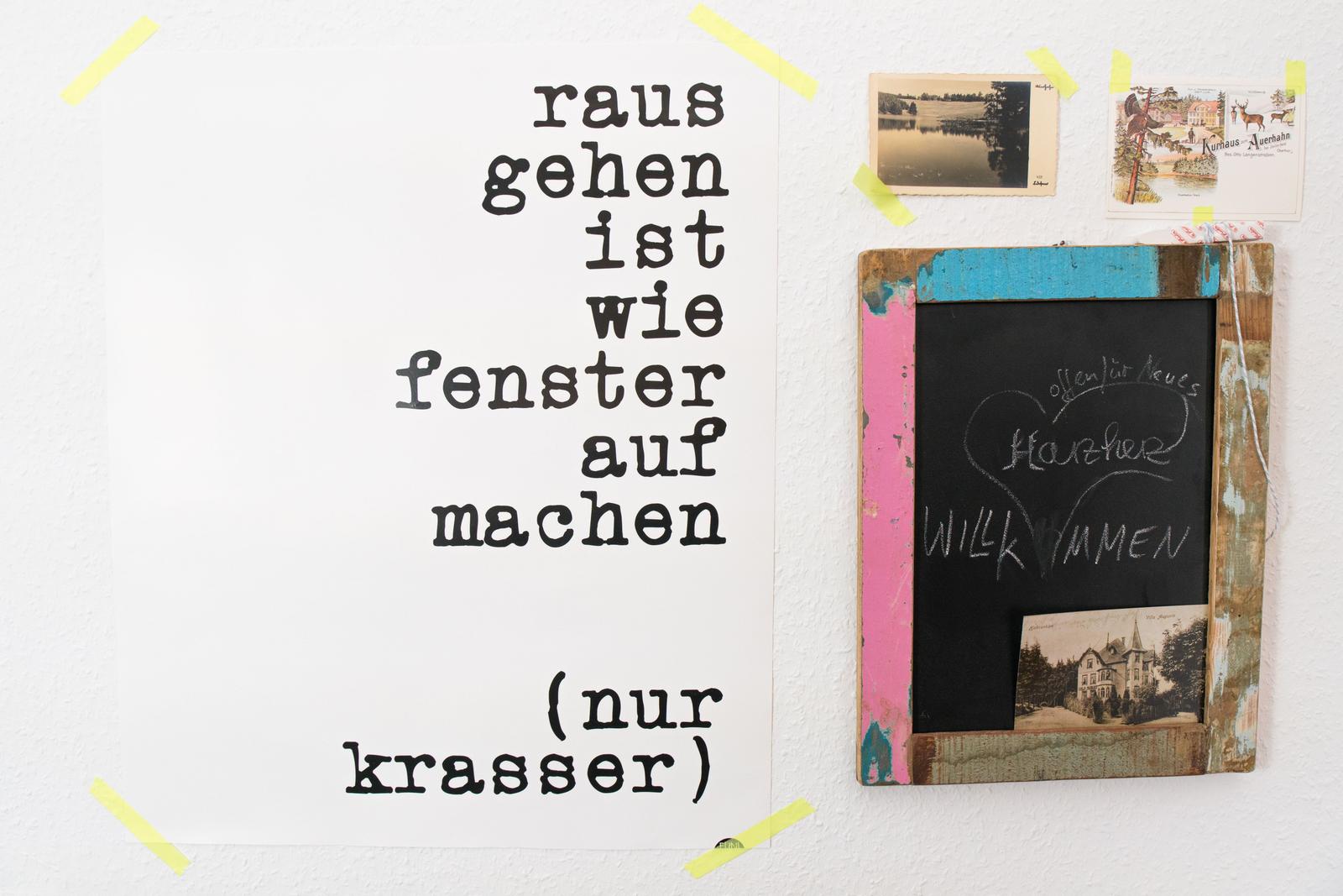 Wand mit Poster und Schiefertafel mit Postkarten und Handschrift.