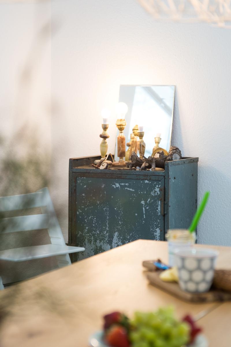 Ein Tisch mit Obst und einer rustikalen Kommode mit Lampen und Spiegel.