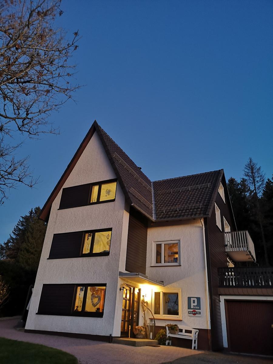 Haus mit beleuchteten Fenstern und Garage bei Dämmerung.
