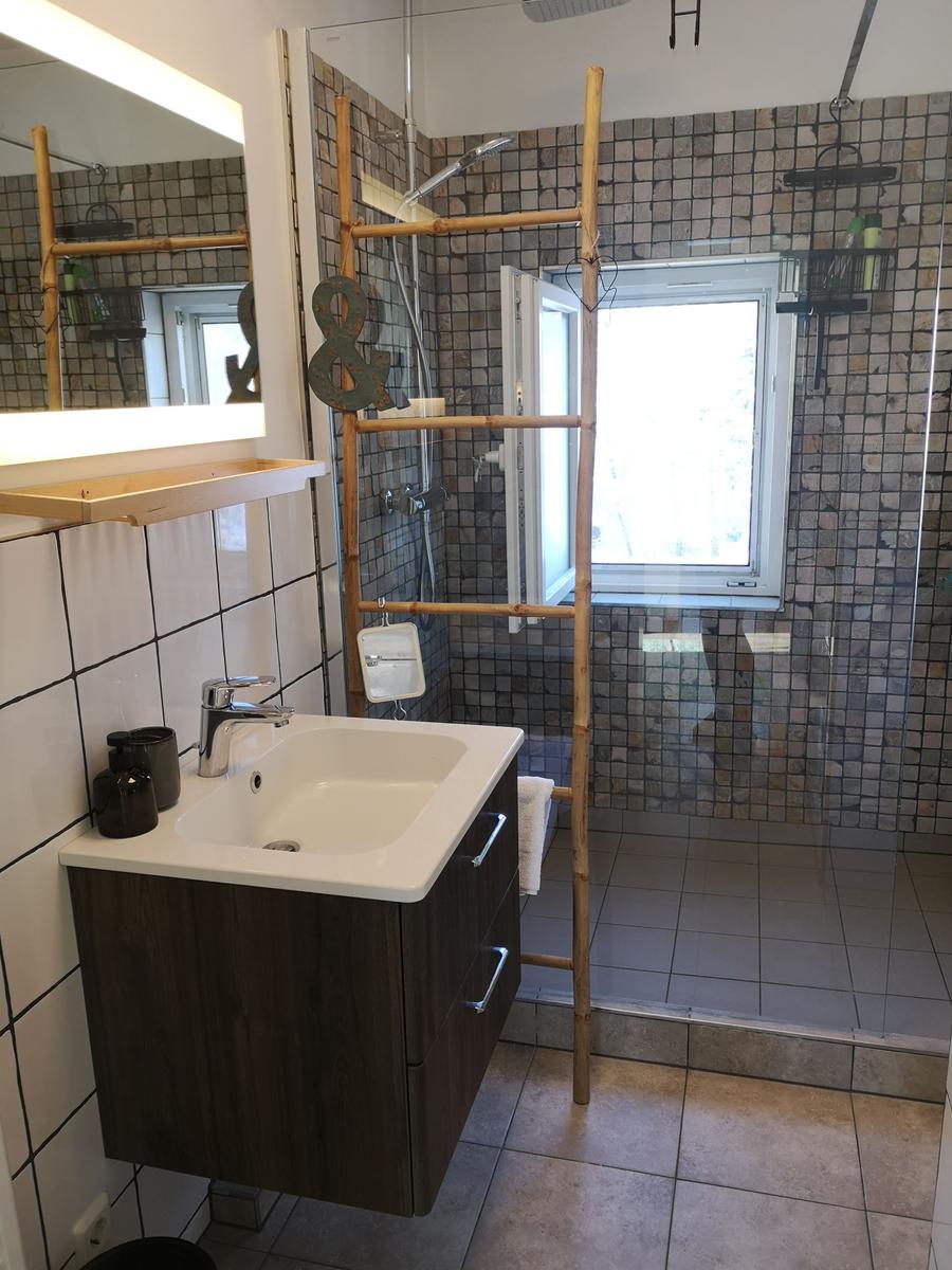 Badezimmer mit Dusche, Waschbecken und Spiegel