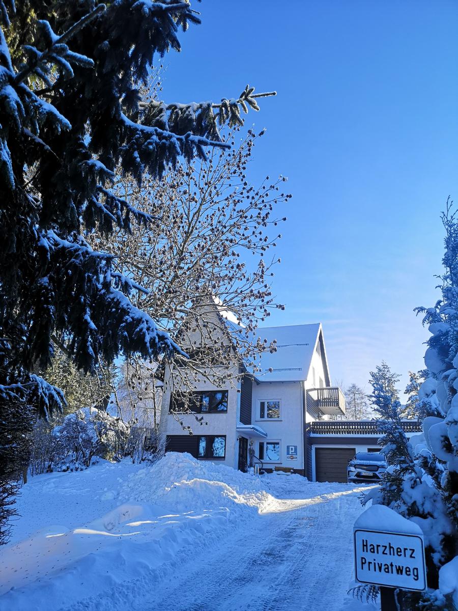 Schneebedecktes Haus mit Garage und Schild Harzherz Privatweg in winterlicher Umgebung.