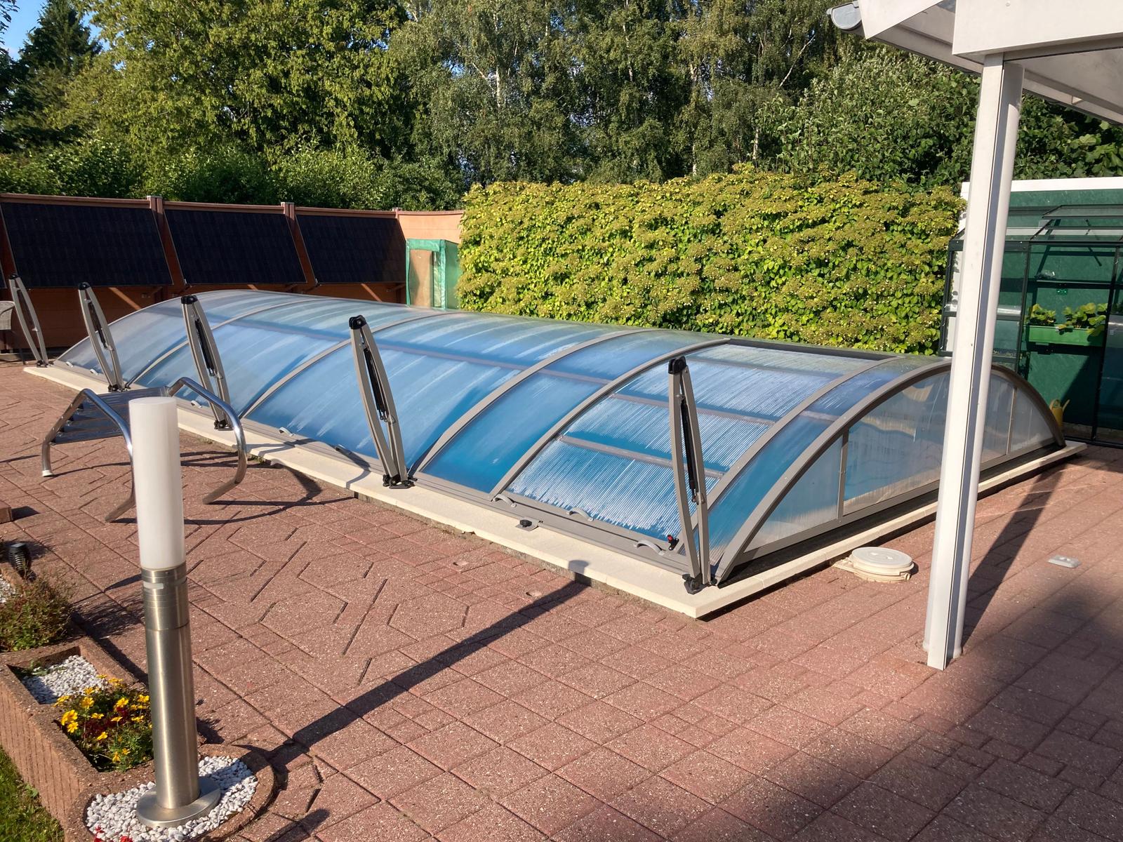 Gewächshaus mit blau getöntem Dach auf gepflastertem Hof.
