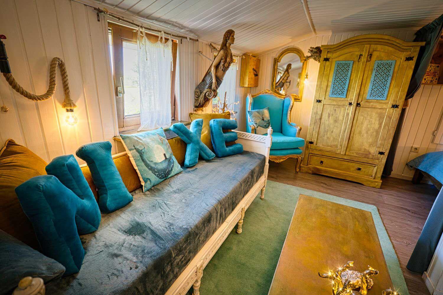 Ein Raum mit Sofa, blauen Kissen und einem goldenen Schrank.