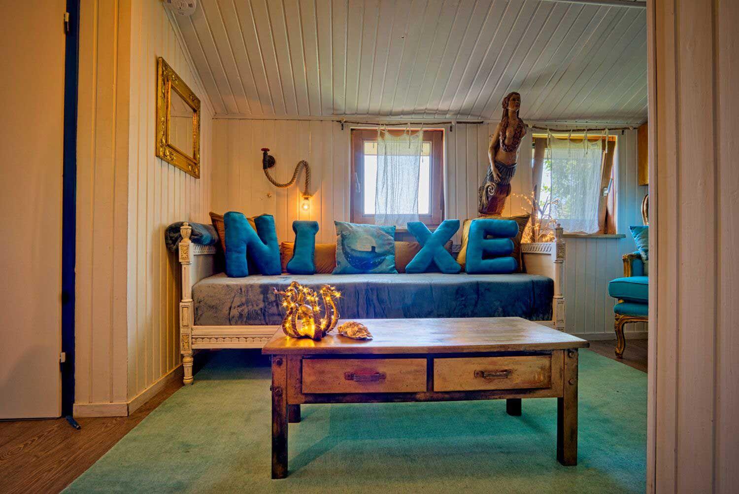 Ein Wohnzimmer mit Sofa, Kissen und Tisch. An der Wand hängt ein Spiegel.