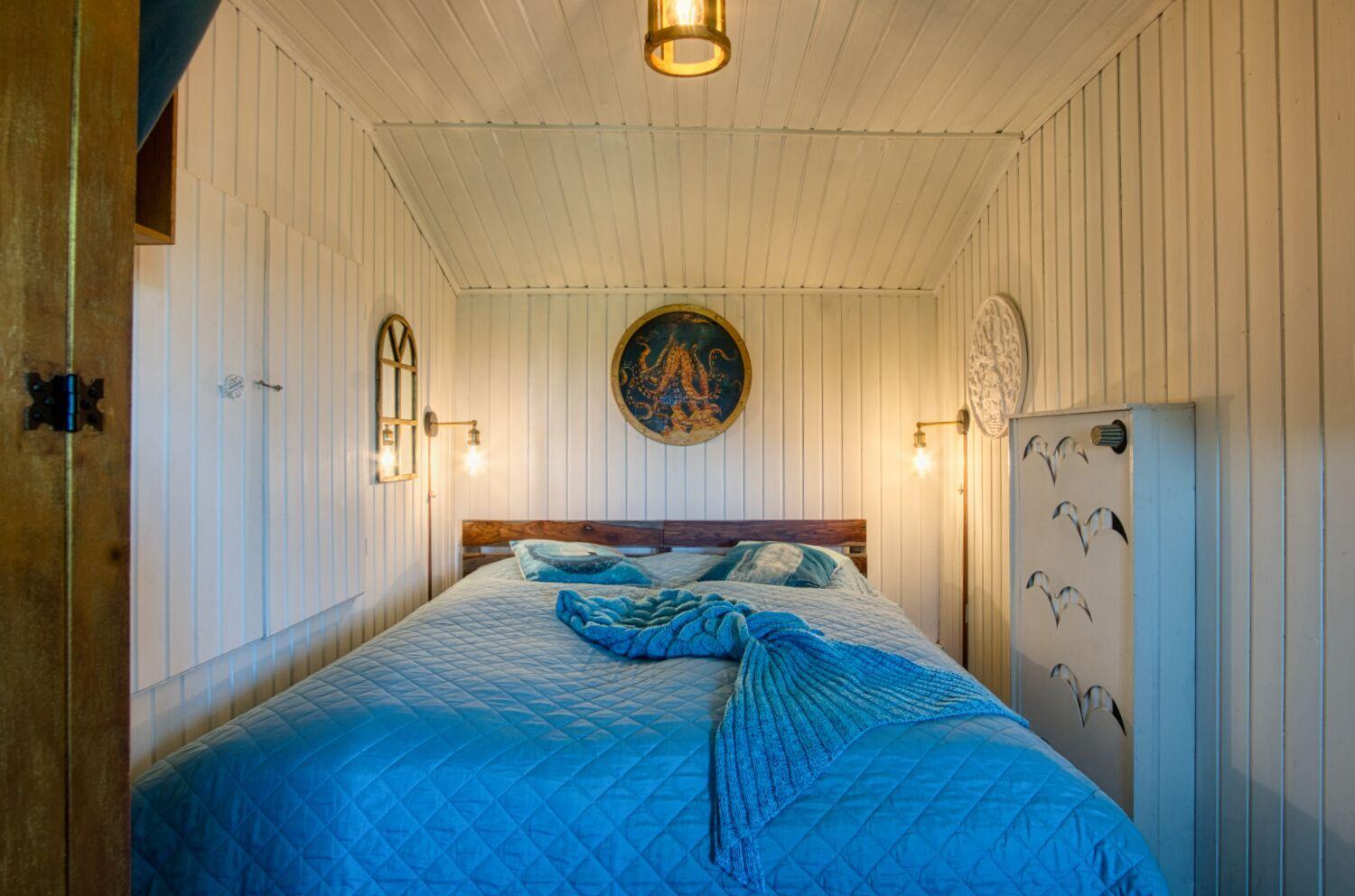Schlafzimmer mit Bett, Wanddekoration und Holzwandverkleidung.