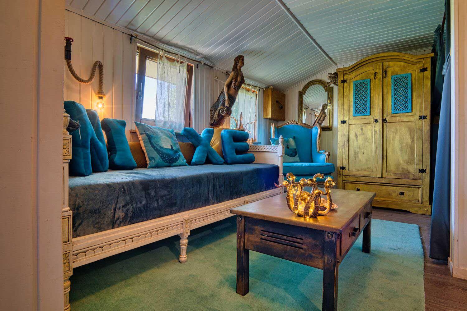 Ein Raum mit blauem Sofa, goldenem Schrank und dekorativen Kissen.