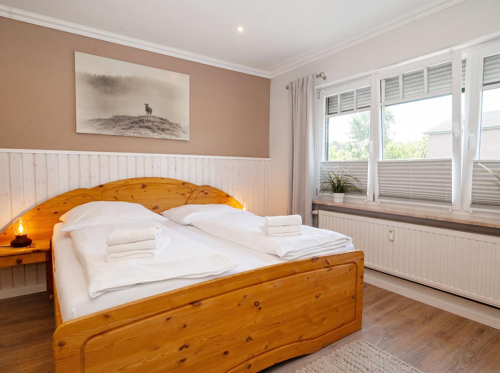 Ein Schlafzimmer mit einem Holzbett, einem Fenster und einer Wanddekoration.