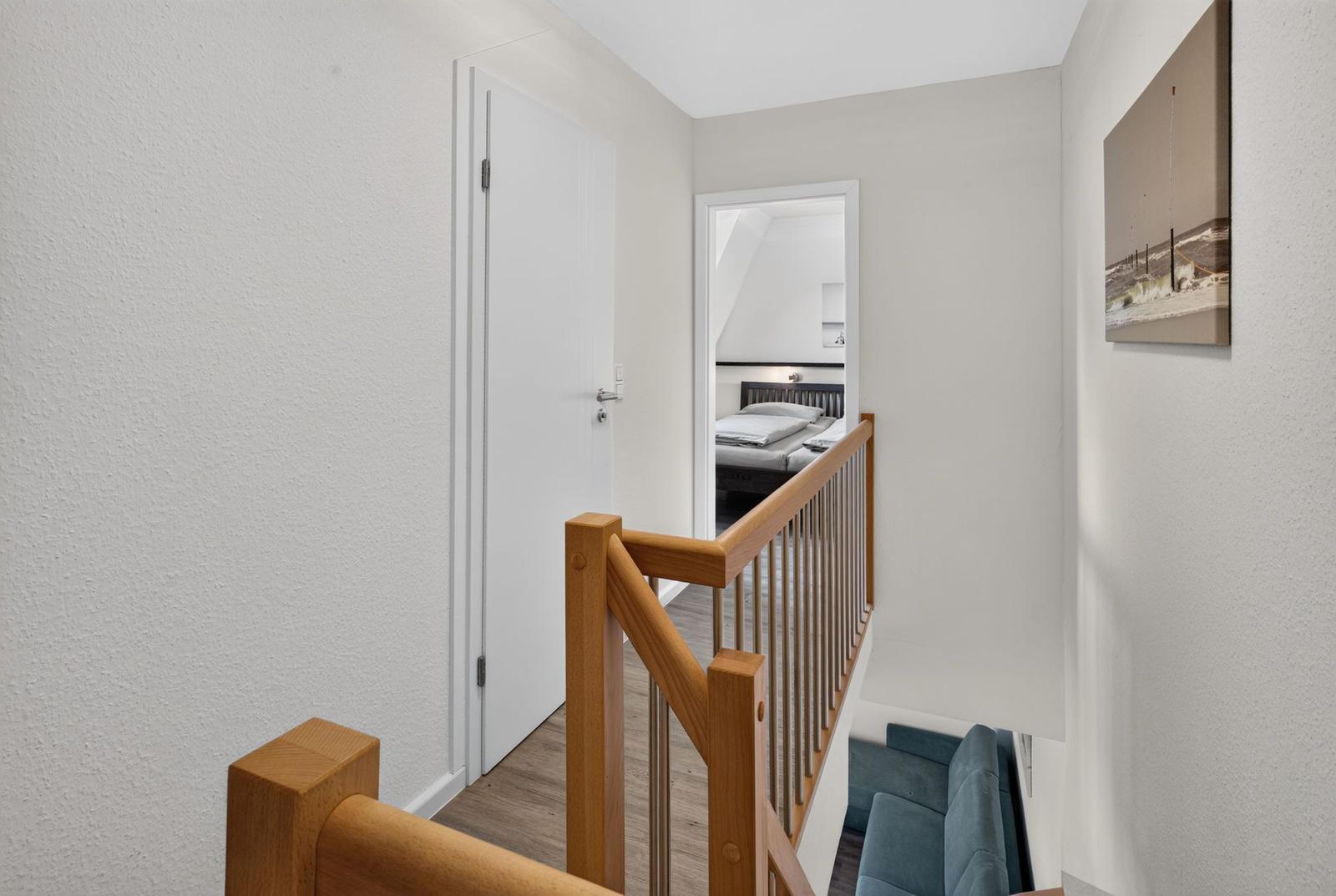 Haus mit Holzgeländer, Schlafzimmer und Wohnbereich im Obergeschoss.