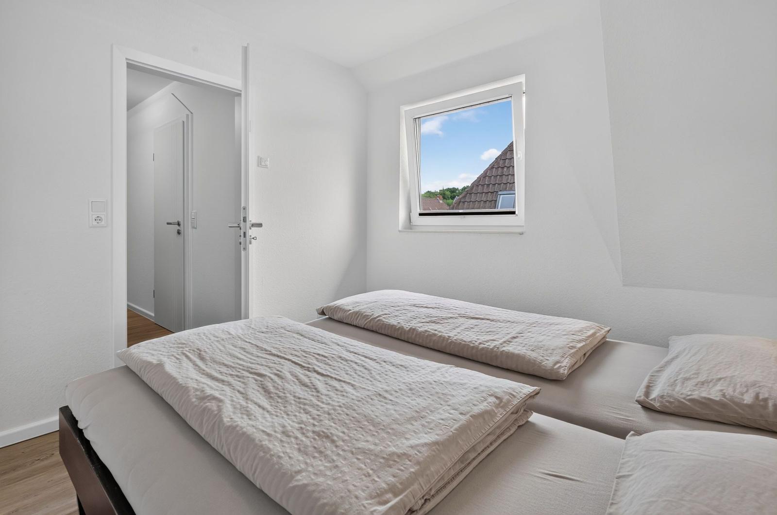 Zimmer mit zwei Betten und Fensterblick auf Dach
